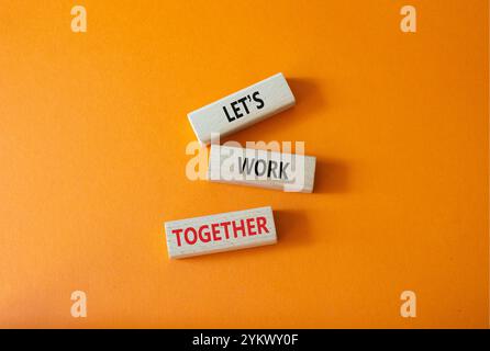 Das Symbol „Zusammenarbeiten“. Konzeptworte weniger ist mehr auf Holzklötzen. Wunderschöner orangefarbener Hintergrund. Business und weniger ist mehr Konzept. Kopierbereich. Stockfoto