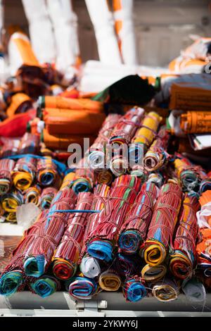 Stapel zusammengerollter, farbenfroher Gebetsfahnen zum Verkauf auf dem Mount Kailash während des Saga Dawa Festivals in Tibet. Stockfoto