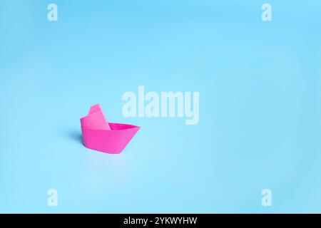 Ein einsames rotes Boot auf blauem Hintergrund, das das Meer symbolisiert. Stockfoto