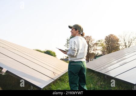 Farmerin mit digitalem Tablet auf einem modernen Bauernhof mit Solarpaneelen. Stockfoto