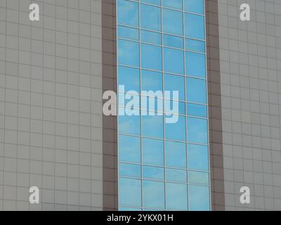 Fragment eines modernen Gebäudes mit blauen Glasfenstern und grau-brauner Vertäfelung, Außendetail der Wand des Geschäftsgebäudes als städtischer Raum Stockfoto
