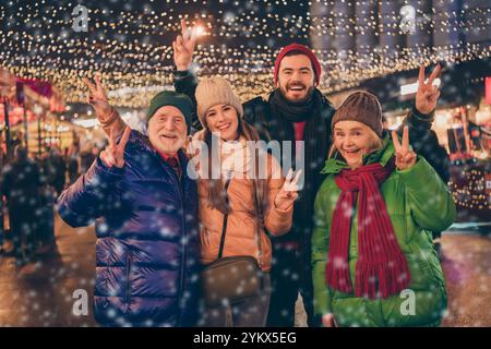 Foto der ganzen großen Familie vier Mitglieder Weihnachten Treffen Versammlung Zeige V-Zeichen fröhlich Gruß santa claus Oberbekleidung gestrickt Hut Schal Coat Night Street Stockfoto