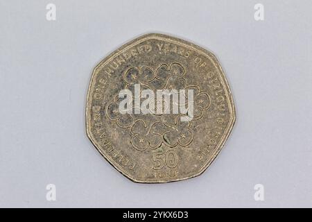 Eine britische 50-Pence-Münze zum Gedenken an das 100-jährige Girl Guiding UK ist auf einem hellgrauen Hintergrund zu sehen. Die Münze hat ein zentrales Design von Stockfoto