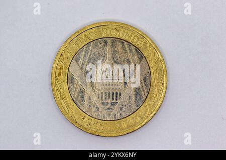 Nahaufnahme einer abgenutzten, goldfarbenen britischen zwei-Pfund-Münze mit St. Paul's Cathedral und den Jahren 1945-2005, vor einem hellgrauen Hintergrund. Stockfoto