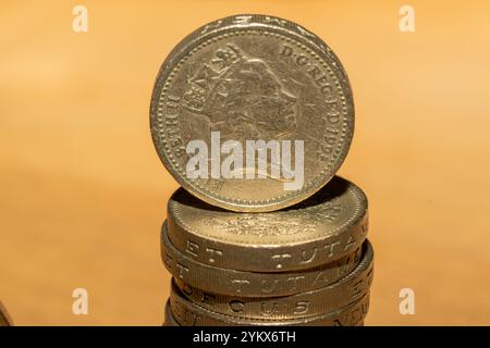 Eine Nahaufnahme zeigt eine einzige britische 1-Pfund-Münze, die auf einem Stapel ähnlicher Münzen balanciert ist. Auf der Vorderseite der obersten Münze mit Königin Elizabeth II. Steht der Kater Stockfoto