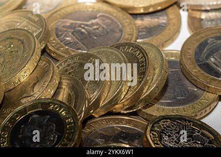 Eine Nahaufnahme eines Stapels britischer 1-Pfund-Münzen, die verschiedene Designs und Jahre zeigen. Die Münzen sind goldfarben mit dunkleren Mittelpunkten, die uns zeigen Stockfoto