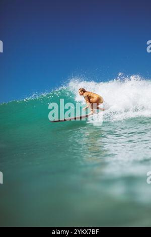 Ein Surfer reitet in Waikiki unter sonnigem Himmel auf einer Welle. Stockfoto