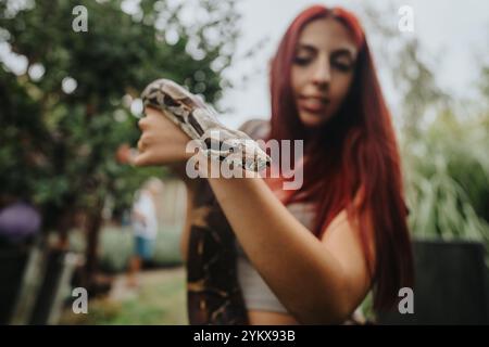 Mädchen mit rotem Haar hält draußen eine große Schlange Stockfoto