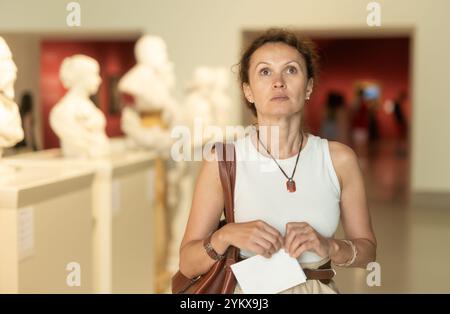 Positive Frau, die alte Basreliefs im alten Museum ansieht Stockfoto