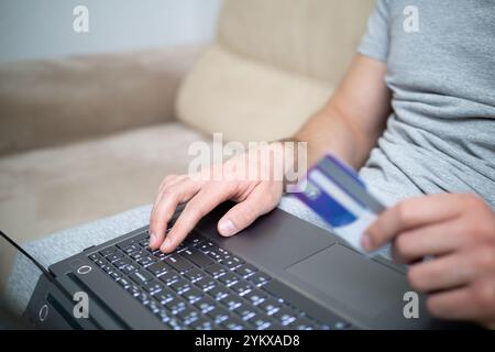 Nahaufnahme von Männerhänden, die auf dem Laptop tippen und Kreditkarte halten Stockfoto