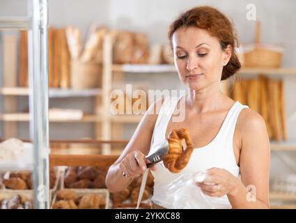 Frau packt Croissant in Plastiktüte in der Bäckerei Stockfoto