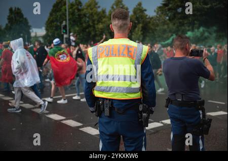 Deutscher Polizist zurück und die Menge der Fußballfans im Hintergrund Stockfoto