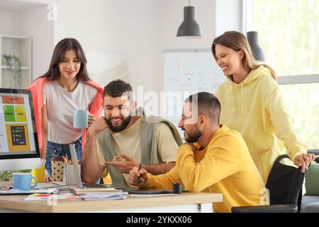 Team von Designern mit einem Mann im Rollstuhl, der im Büro arbeitet Stockfoto