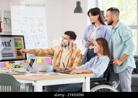 Team von Designern mit Frau im Rollstuhl, die im Büro arbeitet Stockfoto