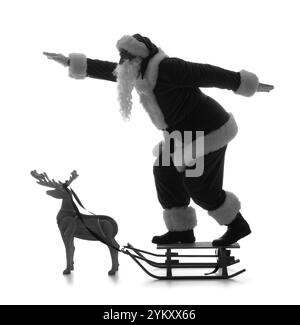 Silhouette des Weihnachtsmanns auf Schlitten und hölzernem Rentier vor weißem Hintergrund Stockfoto