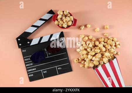 Leckeres Popcorn in Papiereimern, Movie Clapper und 3D-Brillen auf einem bunten Hintergrund. Kinokonzept. Filme ansehen. Kopierbereich Stockfoto