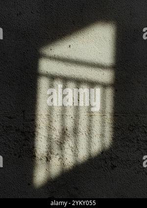 Sonnenlicht-Reflexion: Zaunschatten auf einer Mauer Stockfoto