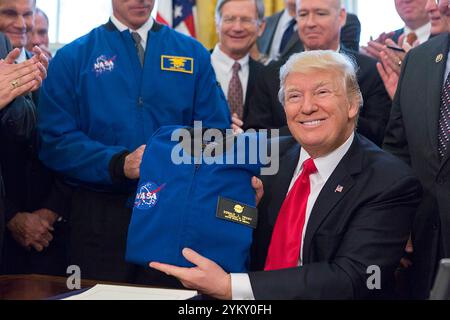 Präsident Donald Trump hält am Dienstag, den 21. März 2017, eine Jacke hoch, die ihm ein Gast gegeben hatte, nachdem er den S-422 National Aeronautics and Space Administration Transition Authorization Act im Oval Office unterzeichnet hatte. (Offizielles Foto des Weißen Hauses von Paul D. Williams) Stockfoto