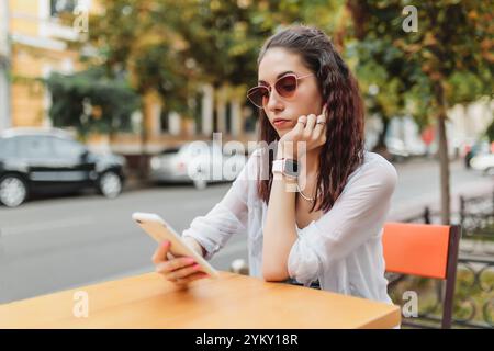 Junge Frau, die Freizeit in einem Café genießt, während sie ihr Smartphone benutzt Stockfoto
