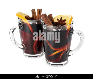 Leckerer Glühwein mit Gewürzen und Orangenscheiben in Tassen isoliert auf weiß. Weihnachtsgetränk Stockfoto