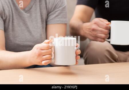 Ein Foto von einem jungen Paar, das eine Tasse Kaffee im Wohnzimmer zu Hause trinkt Stockfoto