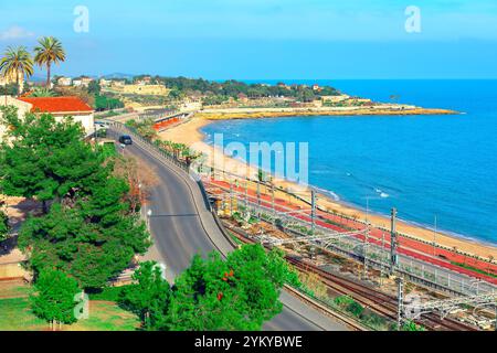 Malerischer Blick auf Tarragona, Spanien, mit einer wunderschönen Küstenlandschaft mit einem Sandstrand. Im Vordergrund verlaufen Straßen- und Eisenbahngleise parallel Stockfoto
