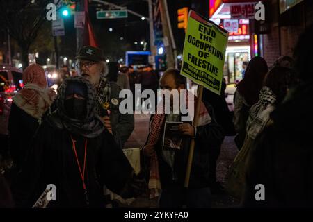 Brooklyn, NY, USA. November 2024. Pro-palästinensische Demonstranten liefen vom Kings Highway die Nostrand Avenue hinunter zur Avenue J in Midwood, trugen Plakate und palästinensische Fahnen, schlugen Trommeln und singen. Die Polizei war außer Kraft, aber es gab keinen Konflikt, und die Demonstranten brachen auf und zerstreuten sich gegen 21:25 Uhr vor Amaryllis, einem in jüdischem Besitz befindlichen Nagelsalon. Während sich die Menge zerstreut, trägt ein Mann ein Plakat mit der Aufschrift „Ende der Besetzung Palästinas“. Quelle: Ed Lefkowicz/Alamy Live News Stockfoto