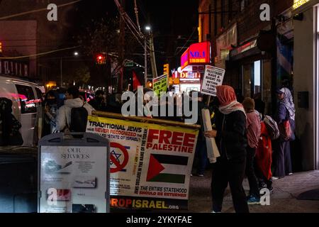Brooklyn, NY - 19. November 2024. Pro-palästinensische Demonstranten liefen vom Kings Highway die Nostrand Avenue hinunter zur Avenue J in Midwood, trugen Plakate und palästinensische Fahnen, schlugen Trommeln und singen. Die Polizei war außer Kraft, aber es gab keinen Konflikt, und die Demonstranten brachen auf und zerstreuten sich gegen 21:25 Uhr vor Amaryllis, einem in jüdischem Besitz befindlichen Nagelsalon. Auf den Plakaten steht: „Ende aller US-Hilfe für Israel“, und auf den anderen steht: „Palästinenser haben das Recht, in ihr Land zurückzukehren.“ Ein Mann, der chassidisch zu sein scheint, trägt ein großes Schild mit der Aufschrift „traditionelle Juden haben nie erkannt Stockfoto