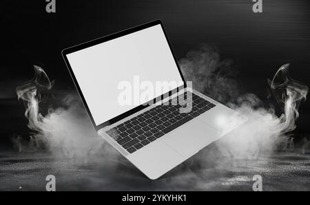 Laptop mit leerem, weißem Bildschirm, der auf einem dunklen Hintergrund einen dramatischen Rauch- oder Nebeleffekt aufweist. Abstraktes Rauchproduktpräsentation mit Spotlight Stockfoto