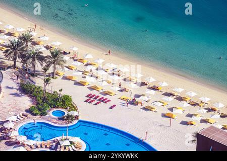 Strand mit Touristen, die die Sonne und das Meer genießen, sitzen unter Sonnenschirmen aus der Vogelperspektive von oben. Stockfoto