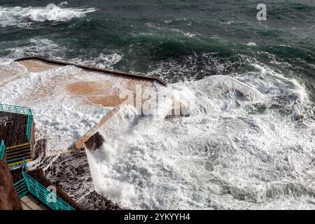 Ein atemberaubender Blick auf die Wellen, die dramatisch gegen die Küstenstrukturen in Funchal, Madeira, prallen und die raue Schönheit des Atlantischen Ozeans zeigen Stockfoto