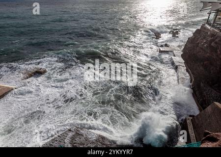 Ein atemberaubender Blick auf die Wellen, die dramatisch gegen die Küstenstrukturen in Funchal, Madeira, prallen und die raue Schönheit des Atlantischen Ozeans zeigen Stockfoto