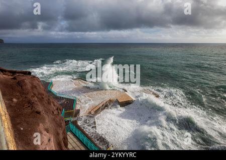 Ein atemberaubender Blick auf die Wellen, die dramatisch gegen die Küstenstrukturen in Funchal, Madeira, prallen und die raue Schönheit des Atlantischen Ozeans zeigen Stockfoto