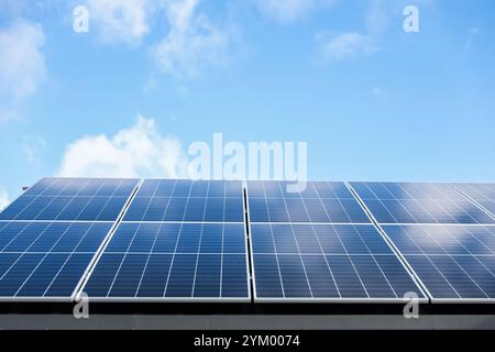 Solarzellen auf wolkenblauem Himmel Hintergrund. Sauberes Konzept für alternative Energie. Modernes Haus mit Solarpaneelen, eigenständige Photovoltaikanlage Stockfoto