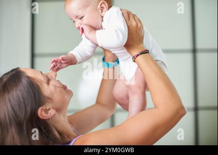 Fröhliche Interaktion zwischen Mutter und Baby in einem hellen Innenraum während des Spielens Stockfoto