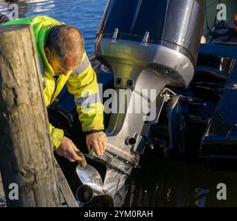 Ein Mann in einer Hi-Viz-Jacke arbeitet am Außenbordmotor eines Motorbootes bei der Coniston Power Boat Records Week 2021 auf Coniston Water im Lake District Stockfoto