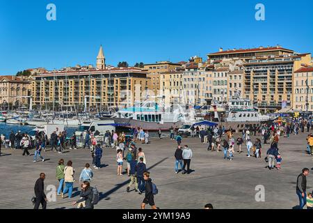 Marseille. Frankreich - 20. November 2024: Menschenmenge spaziert und genießt den sonnigen Tag am Vieux-Port von Marseille mit Booten und historischen Gebäuden Stockfoto