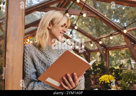 In einem bezaubernden Gewächshaus voller lebendiger Pflanzen sitzt ein junger und gutaussehender Mann und liest ein Buch. Stockfoto