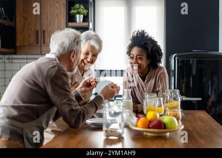 Glückliche multiethnische Familie mit älteren Eltern, die Spaß haben und sich in der Küche unterhalten. Stockfoto