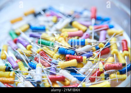 Ein farbenfrohes Sortiment an zahnärztlichen Endodontie-Akten für Wurzelkanalbehandlungen. Nahaufnahme von medizinischen Werkzeugen mit verschiedenen Größen und Farben auf einem verschwommenen Stockfoto