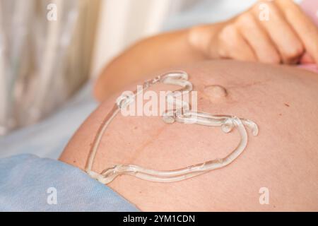 Nahaufnahme eines schwangeren Bauches mit herzförmigem Ultraschallgel, das die pränatale Versorgung und Schwangerschaft hervorhebt Stockfoto