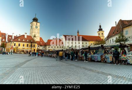 Sibiu, Rumänien - 20. Oktober 2024: Kleine quadratische Handelskioske. Der Stadtturm im Hintergrund. Stockfoto
