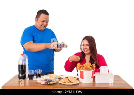 Eine Gruppe von Freunden, die gemeinsam Fast Food genießen, während sie mit einem Smartphone interagieren Stockfoto