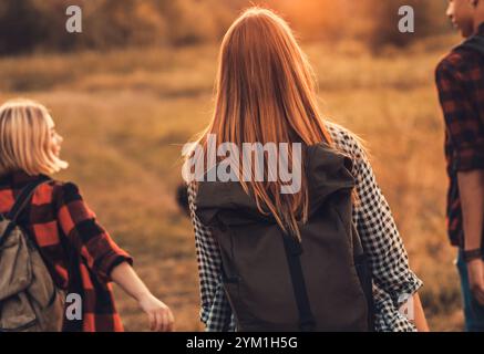 Gruppe von vier Freunden, die gemeinsam bei Sonnenuntergang durch die Landschaft wandern. Stockfoto