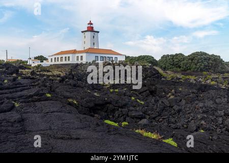 Der Leuchtturm Ponta da Ilha in Manhenha auf der Insel Pico auf den Azoren befindet sich neben einer riesigen Lavastraße. Stockfoto