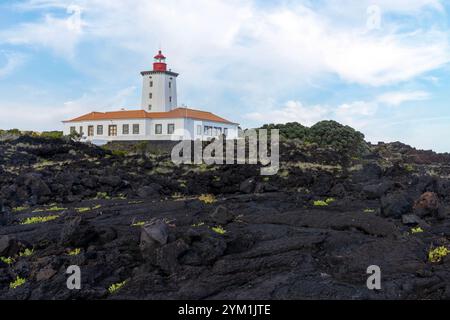 Der Leuchtturm Ponta da Ilha in Manhenha auf der Insel Pico auf den Azoren befindet sich neben einer riesigen Lavastraße. Stockfoto