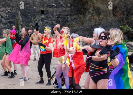 Die Teilnehmer treffen sich am Strand von Towan und bereiten sich auf die jährliche Veranstaltung „Superhero in the Cold“ vor, um Spenden für die britische Krebsforschung zu sammeln. Stockfoto