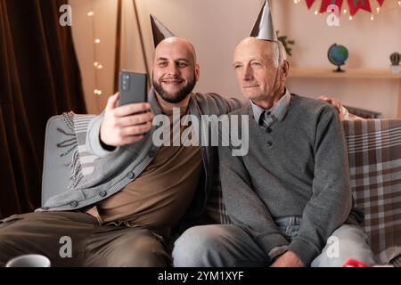 Ein Mann macht Selfies mit seinem älteren Vater während der Feier des Vatergeburts Stockfoto