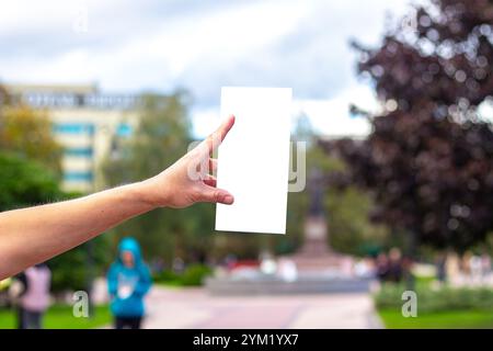 Weibliche Hand mit leerer Broschüre in der Stadt. Broschüre mit Kopierraum. Mock-Up. Leerzeichen für Text Stockfoto
