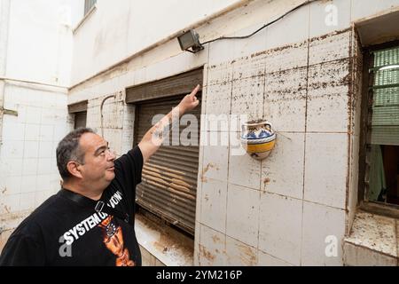 Alfafar, Spanien - 19. November 2024. Vicente, wohnhaft in Alfafar an der Torrente Avenue vor dem parque Alcosa, ließ sein Haus vollständig vom Wasserstrom untertauchen. Er zeigt die Höhe, die durch die Flut erreicht wurde, und zwei Fotos, die von derselben Stelle aufgenommen wurden, zum Fenster und zu den Straßenverhältnissen. In weniger als 15 Minuten stieg das Wasser um mehr als 1 Meter und das Motorrad (auf dem Foto) wurde weggefegt. Zu diesem Zeitpunkt hatten die Behörden noch nicht den roten Alarm gemeldet. Quelle: Roberto Arosio/Alamy Live News Stockfoto